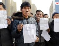 承建商已將工程款給付90%，但包工頭宋林卻把錢拿走不給工人結(jié)工資。一氣之下，十多名工人將包工頭車和人扣下，一不留神卻讓包工頭翻墻跑了。2015年12月31日，在勞動(dòng)監(jiān)察部門協(xié)調(diào)下達(dá)成初步協(xié)議，包工頭將工人手續(xù)移交到成泰公司，由成泰公司替宋林代付一半工資，但在移交工人手續(xù)的時(shí)候包工頭害怕再次被扣卻一直不敢露面。1月3日，包工頭給農(nóng)民工發(fā)來短信，并要求寫下承諾書，保證不扣他本人。圖為1月5日，陜西商洛，討薪農(nóng)民工在工地上出示欠條和他們寫給包工頭的承諾書。華商報(bào)記者 閆文青/視覺中國(guó)