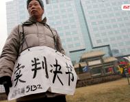 2006年1月24日，在京從事降水井工程的老陳掛著寫有“賣判決書”的紙口袋在北京站口附近來回走著。曾是名小工頭的老陳被欠工程款4萬元，為了給工人們開資不得已賣掉了打井機(jī)器。2002年法院宣判老陳勝訴，可四年后該判決仍得不到執(zhí)行，無奈之中老陳只好上演此幕。程寧/視覺中國(guó)